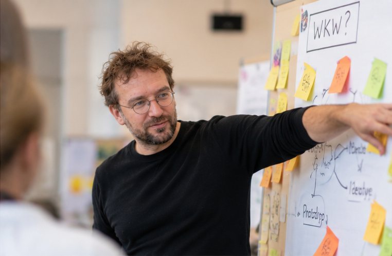 Simon Steiner moderiert einen Design-Thinking-Workshop am Flipchart mit Wie-könnten-wir-Frage